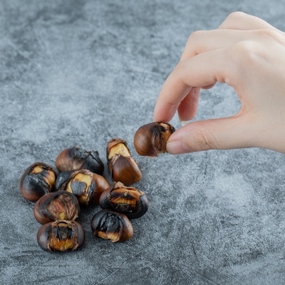 Hand holding roasted chestnut